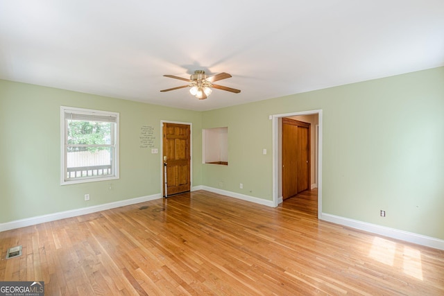 empty room featuring ceiling fan, visible vents, baseboards, and light wood finished floors