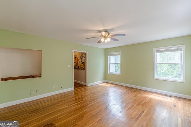 empty room with visible vents, light wood-style floors, ceiling fan, and baseboards