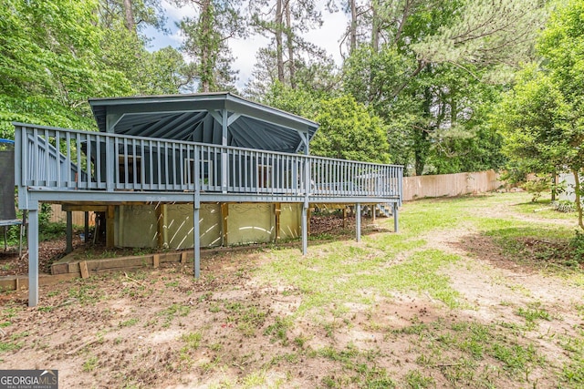 rear view of property featuring fence, a wooden deck, and a trampoline