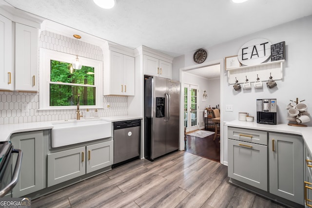 kitchen featuring a sink, light countertops, gray cabinets, stainless steel appliances, and decorative backsplash