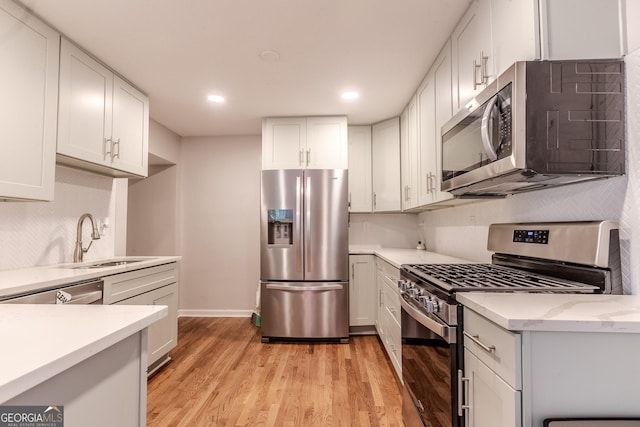 2174 Beecher Rd SW, Atlanta, GA 30311 - kitchen with stainless steel appliances, light wood-style flooring, a sink, and white cabinets