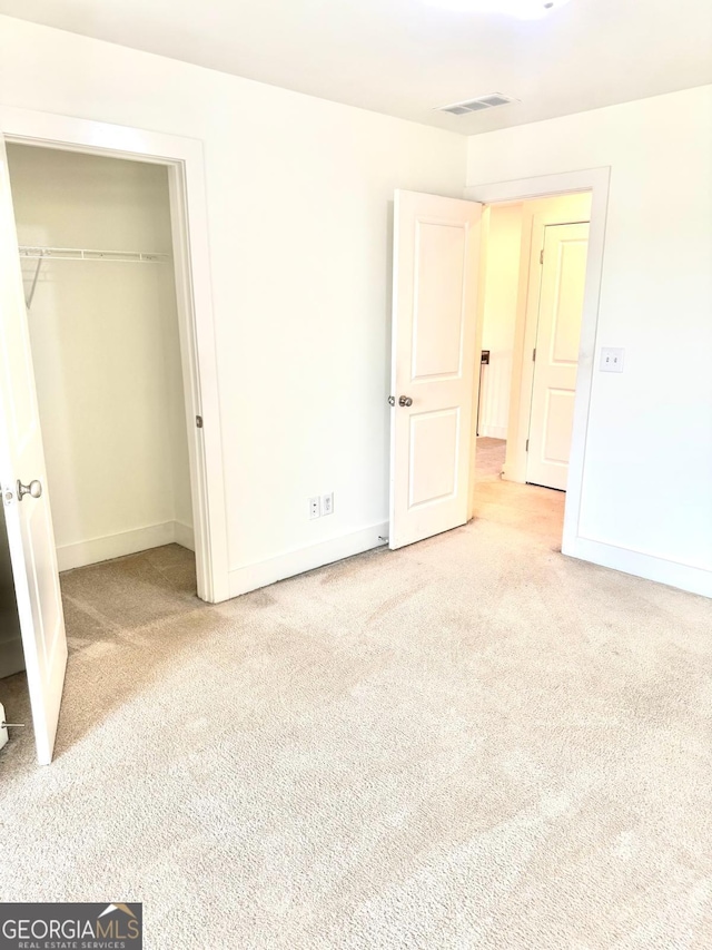unfurnished bedroom featuring visible vents, carpet, baseboards, and a closet