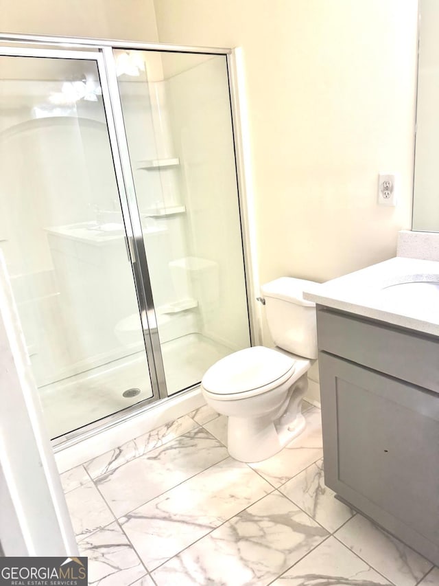 bathroom with vanity, marble finish floor, a stall shower, and toilet