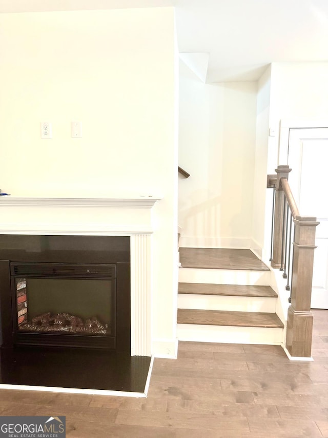 stairway with baseboards, a fireplace, and wood finished floors