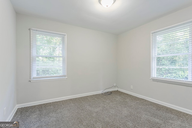 spare room with baseboards and carpet floors
