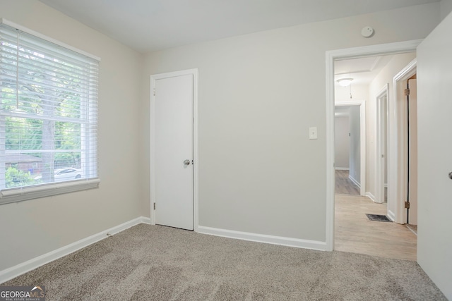 unfurnished room featuring light colored carpet, attic access, visible vents, and baseboards