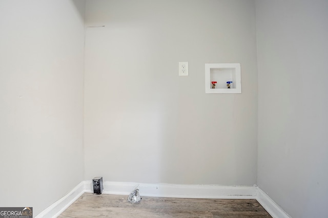 clothes washing area with baseboards, hookup for a washing machine, wood finished floors, and laundry area