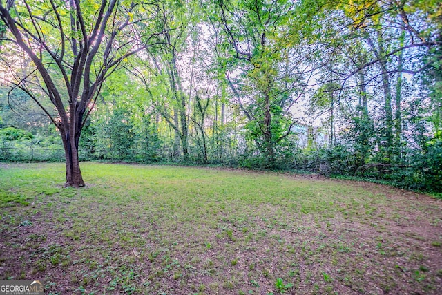 view of yard featuring a wooded view and fence