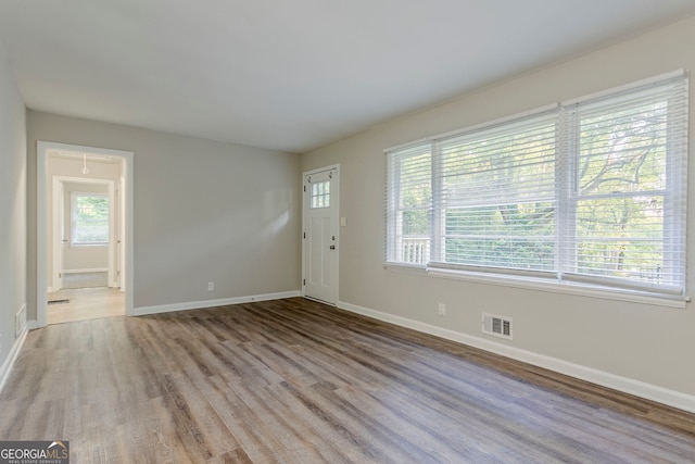 unfurnished living room featuring baseboards, visible vents, wood finished floors, and attic access