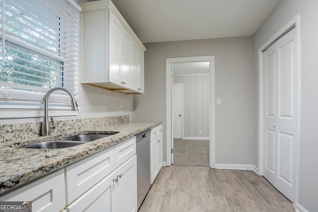 kitchen featuring a sink, light stone counters, light wood-style flooring, stainless steel dishwasher, and white cabinets