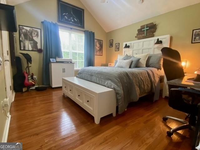 bedroom featuring wood finished floors and lofted ceiling