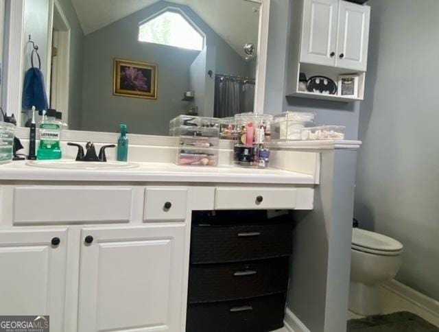 full bathroom with baseboards, toilet, vanity, and vaulted ceiling
