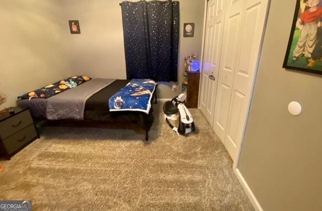 carpeted bedroom featuring baseboards and a closet
