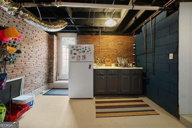 interior space featuring brick wall and freestanding refrigerator