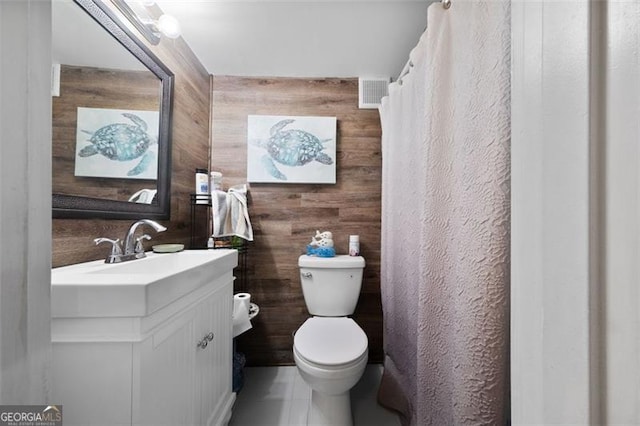 full bathroom featuring visible vents, wooden walls, toilet, vanity, and tile patterned flooring