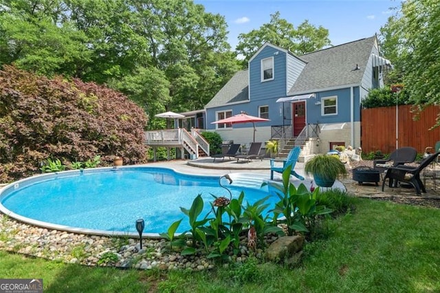 pool with fence, a deck, a patio area, and stairs