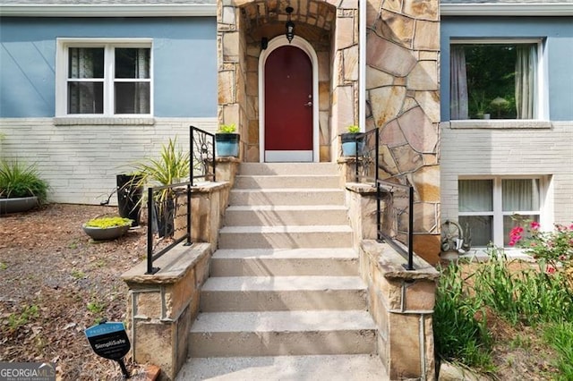 doorway to property with a shingled roof and stone siding
