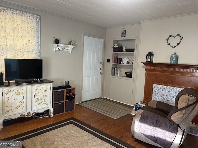 interior space featuring wood finished floors, built in shelves, and ornamental molding