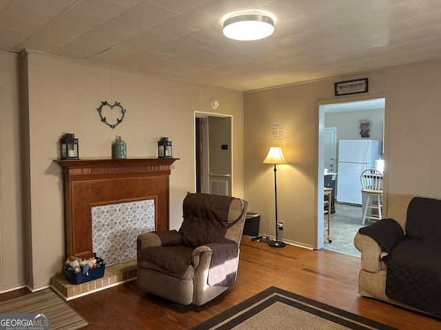 living area featuring baseboards, visible vents, wood finished floors, and ornamental molding
