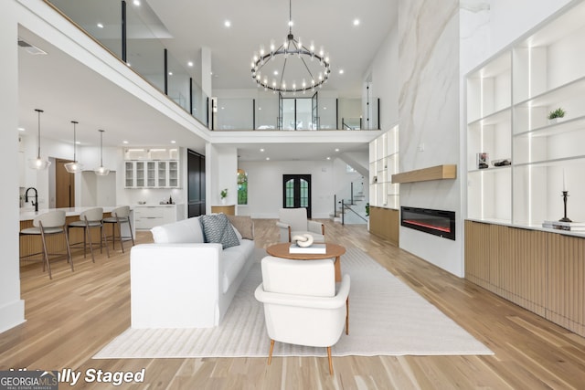 1255 E M Croy Rd, Sugar Hill, GA 30518 - living area featuring a high ceiling, light wood-style flooring, a glass covered fireplace, a chandelier, and recessed lighting
