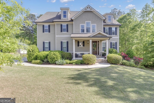 craftsman house with roof with shingles, covered porch, and a front yard