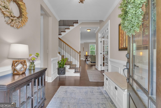 foyer entrance featuring a decorative wall, dark wood-style floors, stairway, a wainscoted wall, and french doors