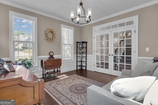 sitting room featuring french doors, crown molding, wainscoting, dark wood-style floors, and a chandelier