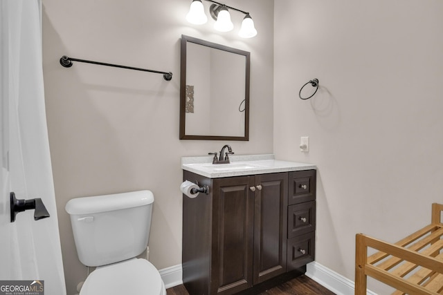 bathroom with baseboards, vanity, toilet, and wood finished floors