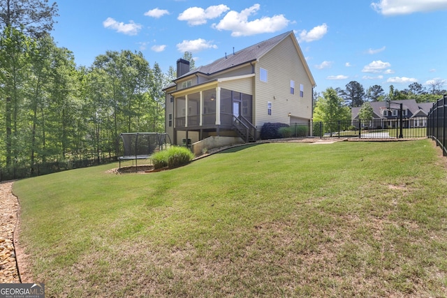 view of yard with a sunroom, a fenced backyard, and a trampoline