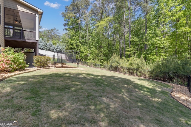 view of yard with a ceiling fan, a fenced backyard, and a trampoline