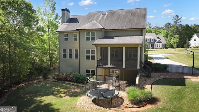 rear view of house featuring fence, a shingled roof, a sunroom, a chimney, and a yard