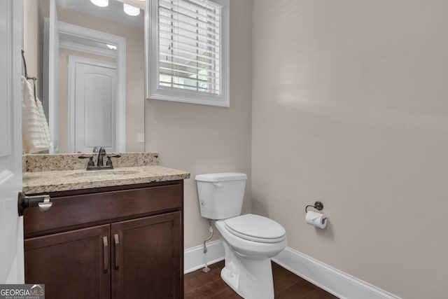 bathroom with baseboards, wood finished floors, toilet, and vanity