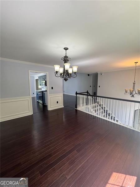 955 Tributary Way, Dacula, GA 30019 - unfurnished dining area with a chandelier, wainscoting, wood finished floors, and crown molding
