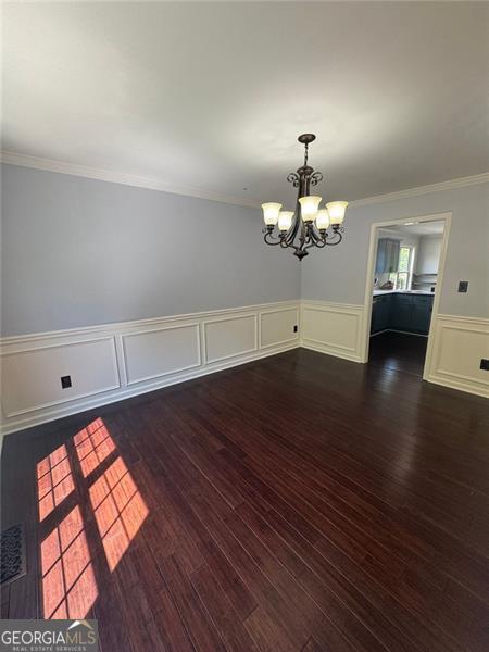 955 Tributary Way, Dacula, GA 30019 - unfurnished dining area with a chandelier, ornamental molding, dark wood-type flooring, wainscoting, and a decorative wall