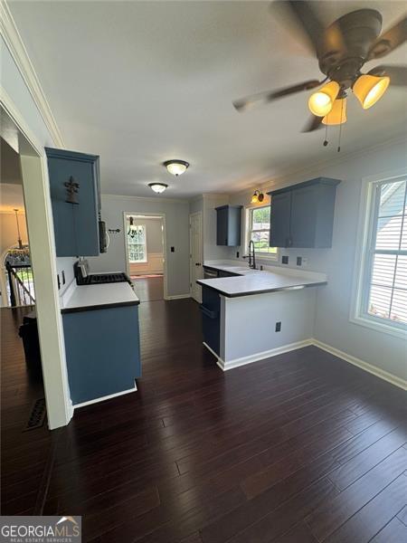 955 Tributary Way, Dacula, GA 30019 - kitchen with ornamental molding, a peninsula, light countertops, ceiling fan, and dark wood-type flooring