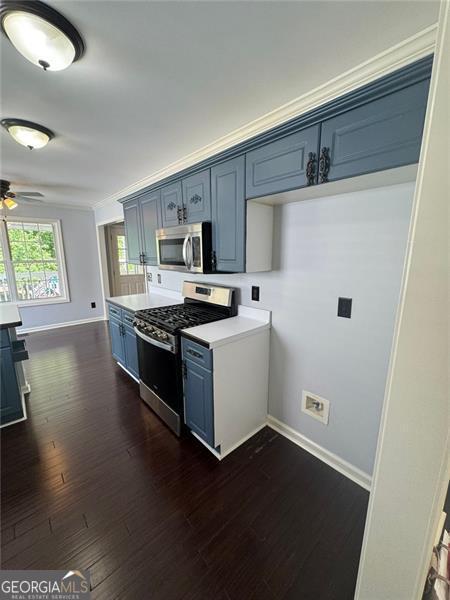 955 Tributary Way, Dacula, GA 30019 - kitchen featuring appliances with stainless steel finishes, blue cabinetry, a ceiling fan, and dark wood finished floors