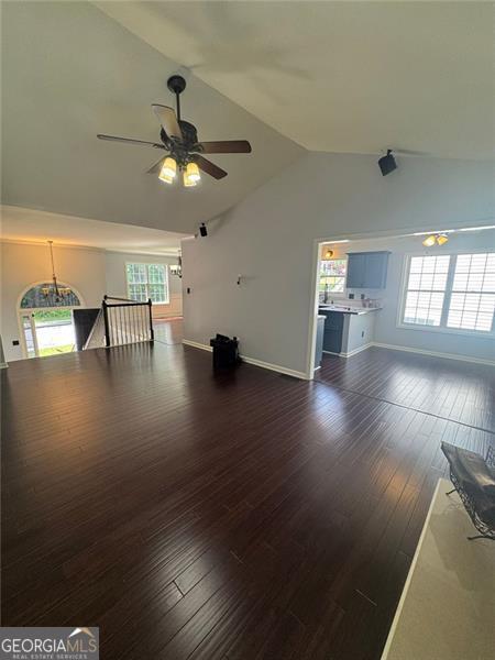 955 Tributary Way, Dacula, GA 30019 - unfurnished living room featuring vaulted ceiling, ceiling fan, dark wood-style flooring, plenty of natural light, and baseboards