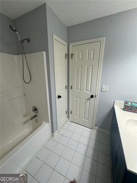 955 Tributary Way, Dacula, GA 30019 - bathroom featuring tile patterned floors, vanity, baseboards, and washtub / shower combination