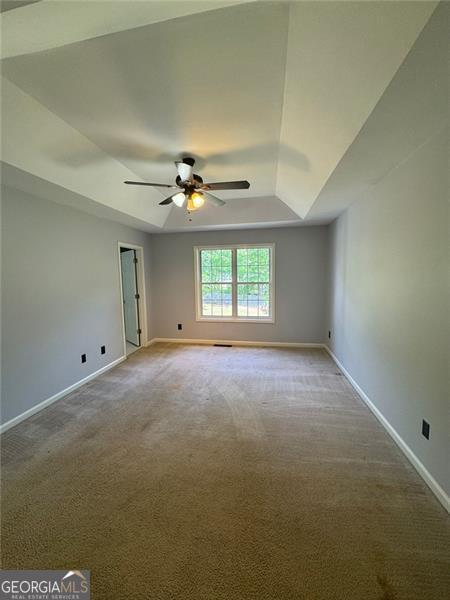 955 Tributary Way, Dacula, GA 30019 - carpeted spare room with a ceiling fan, baseboards, and a tray ceiling