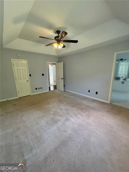 955 Tributary Way, Dacula, GA 30019 - unfurnished living room with a raised ceiling, a ceiling fan, baseboards, carpet floors, and lofted ceiling
