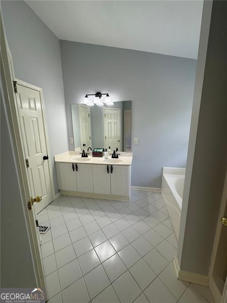 955 Tributary Way, Dacula, GA 30019 - bathroom featuring tile patterned floors, double vanity, and a bath