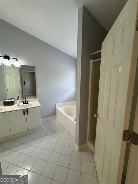 955 Tributary Way, Dacula, GA 30019 - bathroom with vaulted ceiling, a garden tub, vanity, tile patterned flooring, and a shower stall