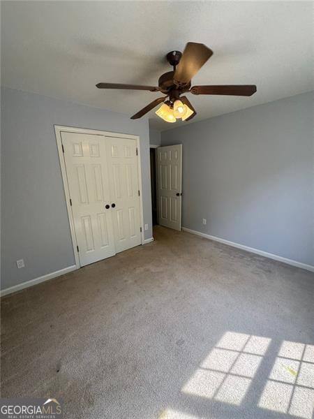 955 Tributary Way, Dacula, GA 30019 - unfurnished bedroom featuring carpet floors, baseboards, a closet, and a ceiling fan