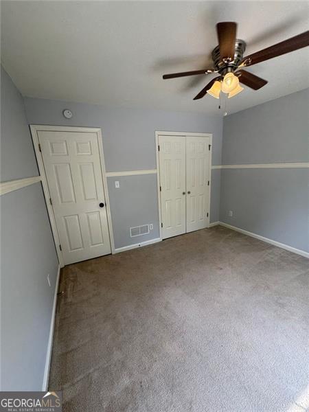 955 Tributary Way, Dacula, GA 30019 - unfurnished bedroom featuring baseboards, carpet, a closet, and a ceiling fan