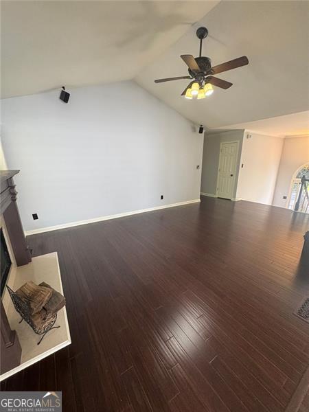 955 Tributary Way, Dacula, GA 30019 - unfurnished living room with a ceiling fan, a glass covered fireplace, vaulted ceiling, baseboards, and wood finished floors