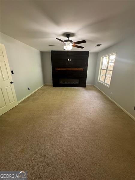 955 Tributary Way, Dacula, GA 30019 - unfurnished living room featuring a ceiling fan, baseboards, carpet, and a fireplace