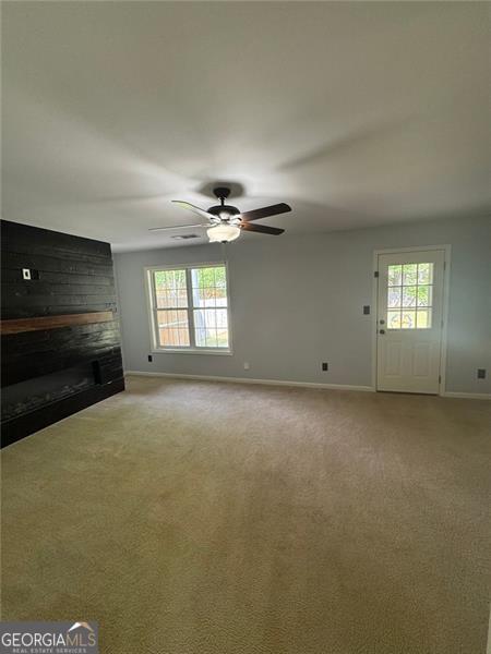 955 Tributary Way, Dacula, GA 30019 - unfurnished living room with baseboards, a brick fireplace, light carpet, and a ceiling fan