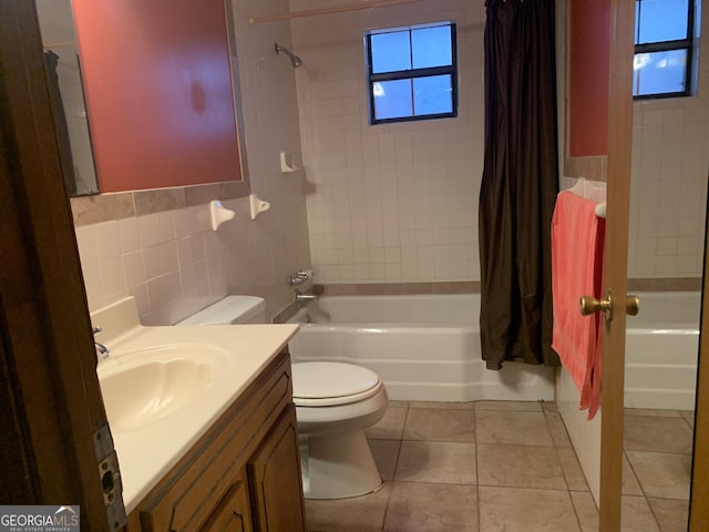 full bath with tile patterned floors, tile walls, shower / bath combo with shower curtain, toilet, and vanity
