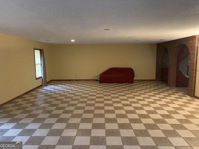 interior space featuring a brick fireplace, recessed lighting, a textured ceiling, and baseboards