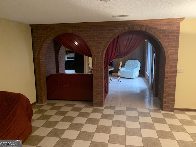 corridor with a textured ceiling, visible vents, and baseboards